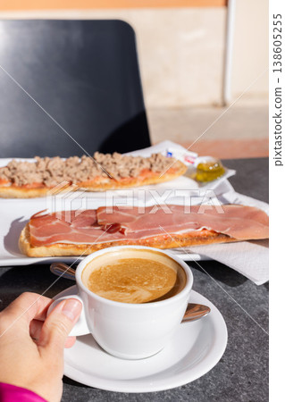 Woman drinking coffee with milk and eating tostada in a cafe outside. 138605255