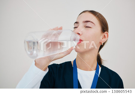 Nurse, woman drinking water in bottle for health, wellness or body nutrition isolated on white background in hospital. Medical professional, hydration and mineral liquid of thirsty surgeon on a break Nurse, woman drinking water in bottle for health, wellness or body nutrition isolated on white background in hospital. Medical professional, hydration and mineral liquid of thirsty surgeon on a break 138605543