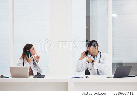 Doctors, talking and people with phone call in office with confidential, info and gesture to whisper. Medical, nurse and busy with administration and frustrated employees with noise or telehealth Doctors, talking and people with phone call in office with confidential, info and gesture to whisper. Medical, nurse and busy with administration and frustrated employees with noise or telehealth 138605711