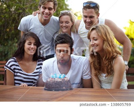 Birthday, people and blow candles outdoor for celebration, surprise or party with milestone or happiness. Cake, men and women in backyard of home or nature with gathering or social event with smile 138605769