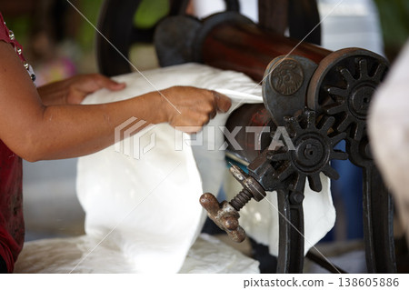 Plastic, industry and hands of person with roller in workshop, factory and outdoor warehouse. Manufacturing, production and worker with machine for rolling latex, rubber and material plantation Plastic, industry and hands of person with roller in workshop, factory and outdoor warehouse. Manufacturing, production and worker with machine for rolling latex, rubber and material plantation 138605886