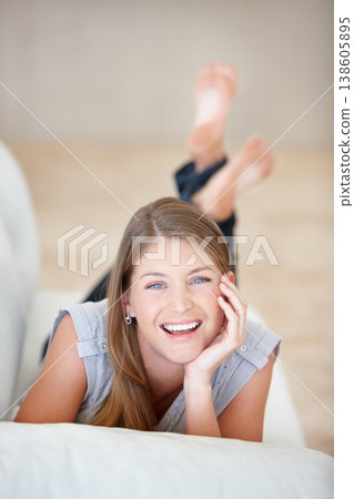 Portrait, smile and relax with a woman on a sofa in the living room of her home on the weekend. Face, natural and a happy young person lying in her apartment for peace or wellness on a break 138605895