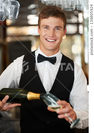 Man, bartender and waiter with champagne at restaurant for happy hour, hospitality industry or customer service. Portrait of barman, server or catering employee smile, wine glass and alcohol bottle 138605924