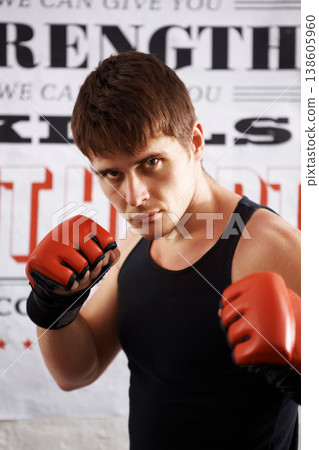 Man, portrait and professional fighter with boxing gloves in martial arts or MMA sports for self defense in dojo. Serious male person, athlete or boxer ready for fight, match or muay thai at the gym Man, portrait and professional fighter with boxing gloves in martial arts or MMA sports for self defense in dojo. Serious male person, athlete or boxer ready for fight, match or muay thai at the gym 138605960