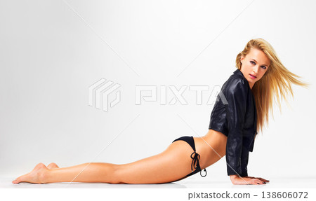 Portrait, leather jacket and woman in lingerie stretching in studio isolated on a white background mockup space. Sexy, serious and model in bikini for fitness exercise, healthy body and flexible legs 138606072