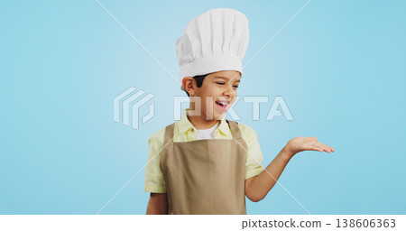 Child, happy face and chef hand to show promotion, advertising or deal in studio. Dress up, profession and young boy happy from future career of cooking and open palm for sale with blue background Child, happy face and chef hand to show promotion, advertising or deal in studio. Dress up, profession and young boy happy from future career of cooking and open palm for sale with blue background 138606363