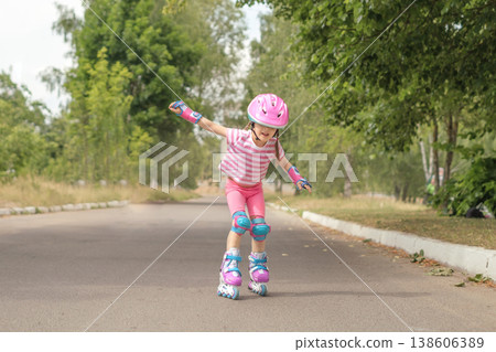 A little girl is trying to keep her balance while learning to rollerblade. Teaching children how to ride fast on roller skates A little girl is trying to keep her balance while learning to rollerblade. Teaching children how to ride fast on roller skates 138606389