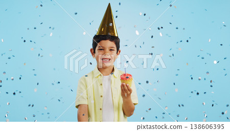 Happy birthday, child and portrait with confetti in party with cupcake, hat and happiness in studio blue background. Congratulations, kid and boy with cake, glitter and smile on face for magic event Happy birthday, child and portrait with confetti in party with cupcake, hat and happiness in studio blue background. Congratulations, kid and boy with cake, glitter and smile on face for magic event 138606395