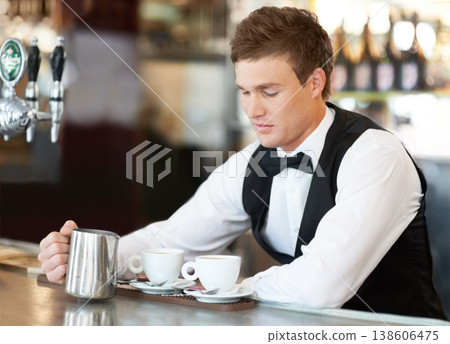 Coffee, barista and young man waiter in cafe making a latte, espresso or cappuccino at an event. Hospitality, server and male butler preparing a warm beverage in a mug or cup by a bar in restaurant. Coffee, barista and young man waiter in cafe making a latte, espresso or cappuccino at an event. Hospitality, server and male butler preparing a warm beverage in a mug or cup by a bar in restaurant. 138606475