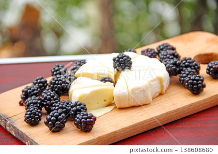 Cheese with blueberries on a wooden board. Sliced cheese with berries Cheese with blueberries on a wooden board. Sliced cheese with berries 138608680