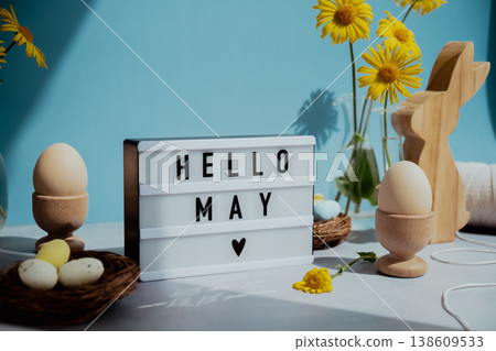 Lightbox with message HELLO MAY on festive blue background and eco-friendly zero waste natural decoration. Yellow daisies flowers. Bunny egg. Holiday greeting 138609533