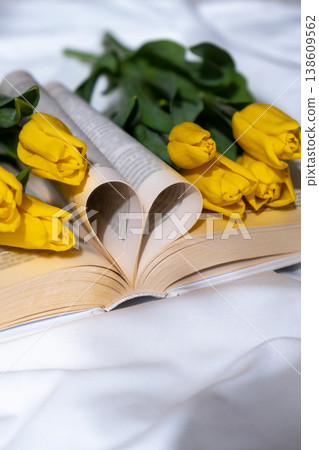 Book pages in shape of heart symbol love with bouquet of pink tulips on messy bed. Romantic morning scene. Greeting card Holiday flowers springtime 138609562