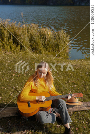 Blonde woman playing string guitar outdoors in autumn forest. Concept of sound therapy, mental health and wellness rituals. Calmness tranquility audio-sensory practices. Aura farming energy Blonde woman playing string guitar outdoors in autumn forest. Concept of sound therapy, mental health and wellness rituals. Calmness tranquility audio-sensory practices. Aura farming energy 138609585