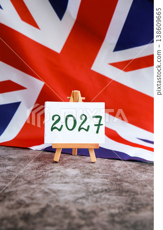 Paper note with text 2027 on National symbol of Great Britain. British wave the UK silky flag background. Financial outlook planning, new year annual report Paper note with text 2027 on National symbol of Great Britain. British wave the UK silky flag background. Financial outlook planning, new year annual report 138609665