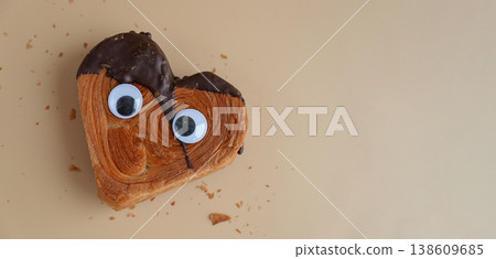 Funny food game face with crazy eyes April fool day joke Delightful and vibrant heartshaped pastry croissant treat, beautifully topped with colorful frosting galore. Food experimentation dessert 138609685
