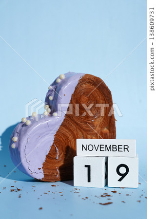 19 November calendar date International Men's Day celebration Heart shaped blueberry flavor croissant on blue background with copy space. Puff pastry new trendy sweet dessert bakery. Creamy dough 138609731