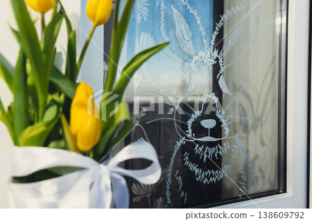 Creative enthusiastic unrecognizable woman paint window with white marker. Easter bunny rabbit decoration on big clear window. Springtime idea home decoration Creative enthusiastic unrecognizable woman paint window with white marker. Easter bunny rabbit decoration on big clear window. Springtime idea home decoration 138609792