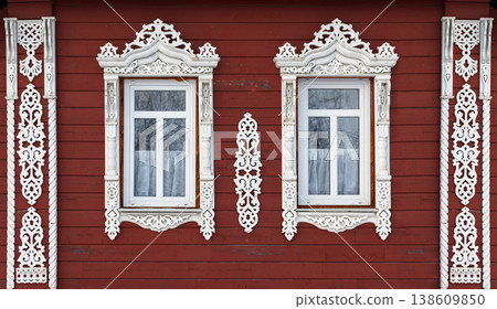 Pair of ornate white carved wooden windows in red wall Pair of ornate white carved wooden windows in red wall 138609850