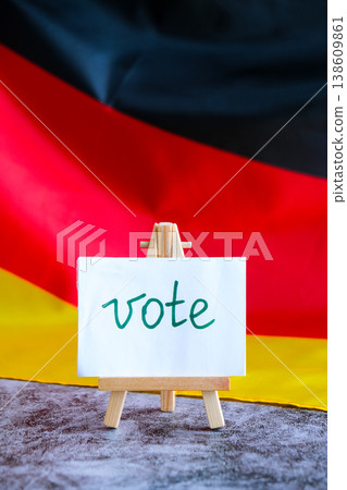 Paper note with words VOTE on National symbol of Germany. German wave silky flag background. Ellection political participation campaign and civic engagement Paper note with words VOTE on National symbol of Germany. German wave silky flag background. Ellection political participation campaign and civic engagement 138609861