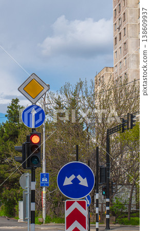 Various blue and yellow traffic signs positioned in front of a tall brutalist apartment block Various blue and yellow traffic signs positioned in front of a tall brutalist apartment block 138609937