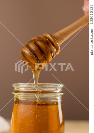 Jar of honey with wooden dipper, sweet liquid, neutral background 138610122
