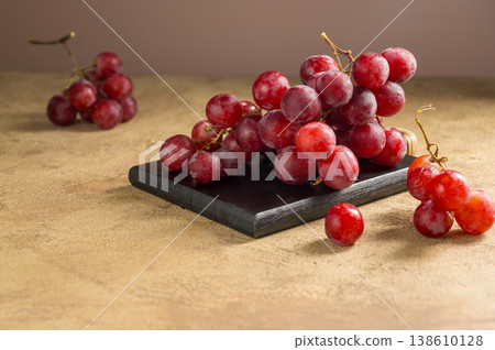 Pink grapes on brown neutral background, autumn harvest concept. Pink grapes on brown neutral background, autumn harvest concept. 138610128