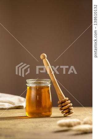 Jar of honey with wooden dipper, sweet liquid, neutral background, copy space Jar of honey with wooden dipper, sweet liquid, neutral background, copy space 138610132