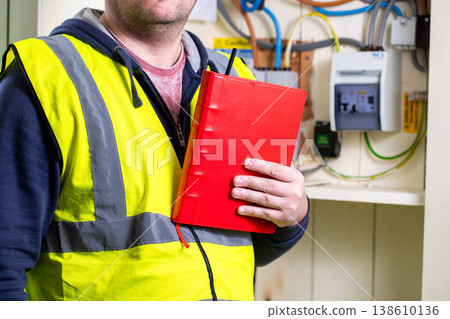Engineer in front of electricity meter indoors checking the meter Engineer in front of electricity meter indoors checking the meter 138610136