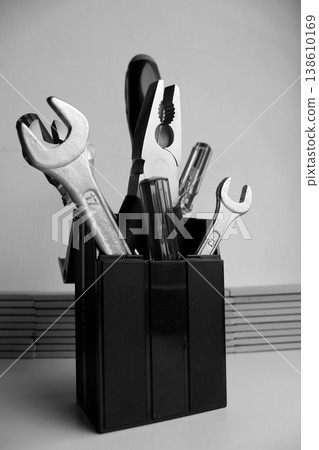 Bunch of carpentry tools in black plastic cup. Monochrome stock photo for workshop illustration  138610169