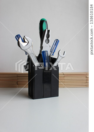 Bunch of multicolored tools in black plastic cup on a clean white table. Stock photo for workshop illustration Bunch of multicolored tools in black plastic cup on a clean white table. Stock photo for workshop illustration 138610184