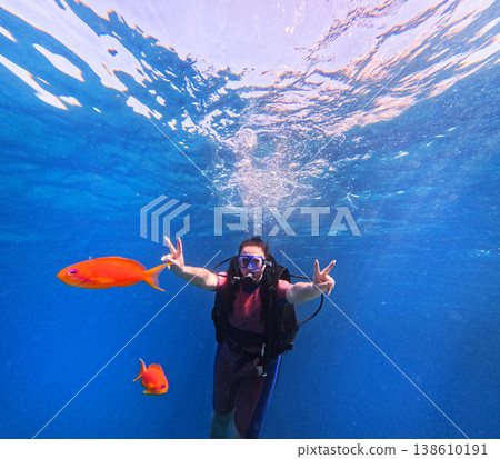 Woman scuba diving with tropical fish feeling freedom underwater 138610191