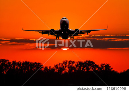 Passenger airliner landing against the backdrop crimson sunset Passenger airliner landing against the backdrop crimson sunset 138610996