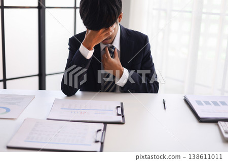 Businessman experiencing stress at work due to heavy workloads, financial worries, and the pressure of responsibility. Businessman experiencing stress at work due to heavy workloads, financial worries, and the pressure of responsibility. 138611011
