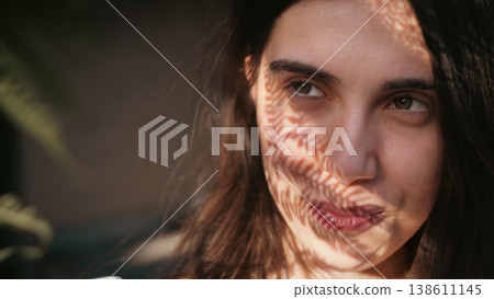Close portrait of young woman with leaf shadow pattern Close portrait of young woman with leaf shadow pattern 138611145