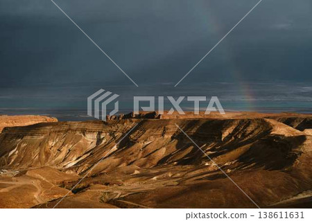Dramatic rainbow over desert landscape with storm clouds and sea view Dramatic rainbow over desert landscape with storm clouds and sea view 138611631