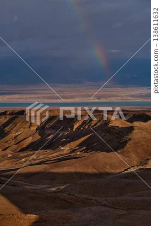 Dramatic rainbow over desert landscape with storm clouds and sea view Dramatic rainbow over desert landscape with storm clouds and sea view 138611632