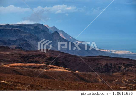 Dramatic desert coastline landscape with storm clouds over calm sea Dramatic desert coastline landscape with storm clouds over calm sea 138611656