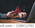 A person using a smartphone and laptop with a red warning alert icon, representing cybersecurity threat, malware attack, phishing, or data breach risk in the digital environment. 138611762