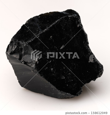 Large Polished Black Obsidian Stone Fragment with Sharp Edges and Glassy Texture Isolated on White Background. 138612049