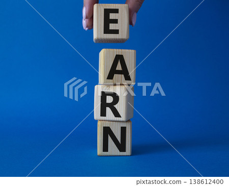 Earn symbol. Concept word Earn on wooden cubes. Businessman hand. Beautiful blue background. Business and Earn concept. Copy space. 138612400