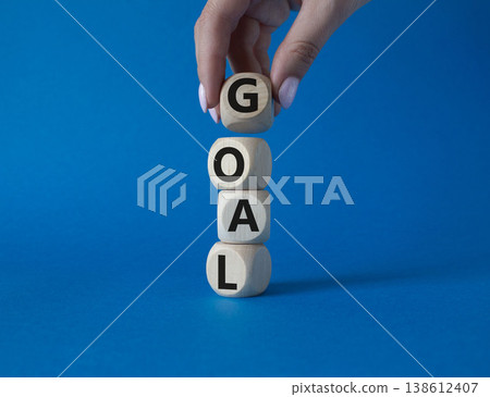 Goal symbol. Concept word Goal on wooden cubes. Beautiful blue background. Businessman hand. Business and Goal concept. Copy space. Goal symbol. Concept word Goal on wooden cubes. Beautiful blue background. Businessman hand. Business and Goal concept. Copy space. 138612407