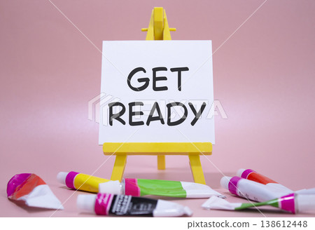 Get ready symbol. Wooden blocks with words Get ready. Beautiful pink background with paints and easel. Business and Get ready concept. Copy space. 138612448