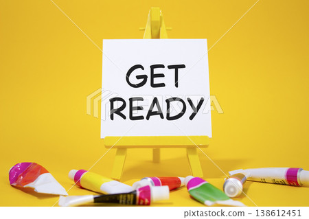 Get ready symbol. Wooden blocks with words Get ready. Beautiful yellow background with paints and easel. Business and Get ready concept. Copy space. 138612451