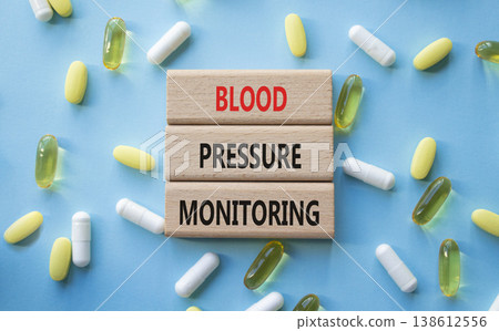 Blood Pressure Monitoring symbol. Concept words Blood Pressure Monitoring on wooden blocks. Beautiful blue background with pills. Healthcare and Blood Pressure Monitoring concept. Copy space. Blood Pressure Monitoring symbol. Concept words Blood Pressure Monitoring on wooden blocks. Beautiful blue background with pills. Healthcare and Blood Pressure Monitoring concept. Copy space. 138612556
