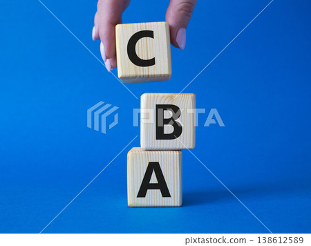 CBA - Cost Benefit Analysis symbol. Wooden cubes with word CBA. Beautiful blue background. Businessman hand. Business and Cost Benefit Analysis concept. Copy space. CBA - Cost Benefit Analysis symbol. Wooden cubes with word CBA. Beautiful blue background. Businessman hand. Business and Cost Benefit Analysis concept. Copy space. 138612589