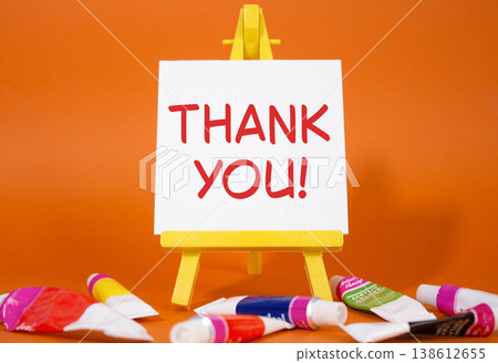 Thank you symbol. Wooden blocks with words Thank you. Beautiful orange background with paints and easel. Business and Thank you concept. Copy space. 138612655