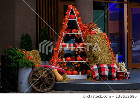 A festive outdoor autumn aesthetic decoration facade with pumpkins and hay bales on a building porch A festive outdoor autumn aesthetic decoration facade with pumpkins and hay bales on a building porch 138612686