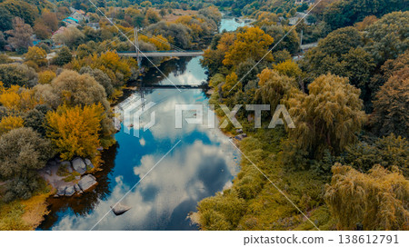 Aerial view of a tranquil river winding through autumn trees and a small village 138612791
