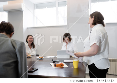 Female team members eating pastries and drinking coffee at conference table during business meeting. Pastries, coffee, business, team, meeting, office. Female team members eating pastries and drinking coffee at conference table during business meeting. Pastries, coffee, business, team, meeting, office. 138612812