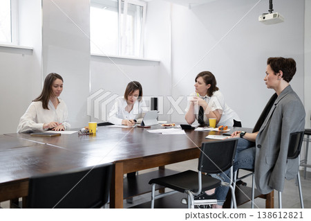 Team at end of breakfast meeting, seated at conference table with leftover pastries and coffee. Breakfast, team, coffee, pastries, conference, meeting, office. 138612821